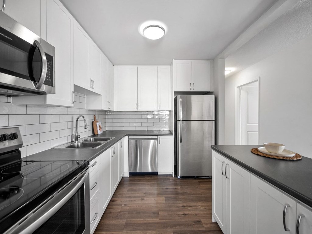 a kitchen with white cabinetry and black countertops