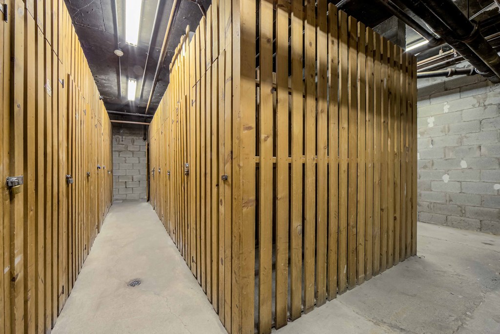 a large wooden gate in a room with concrete floors and a brick wall