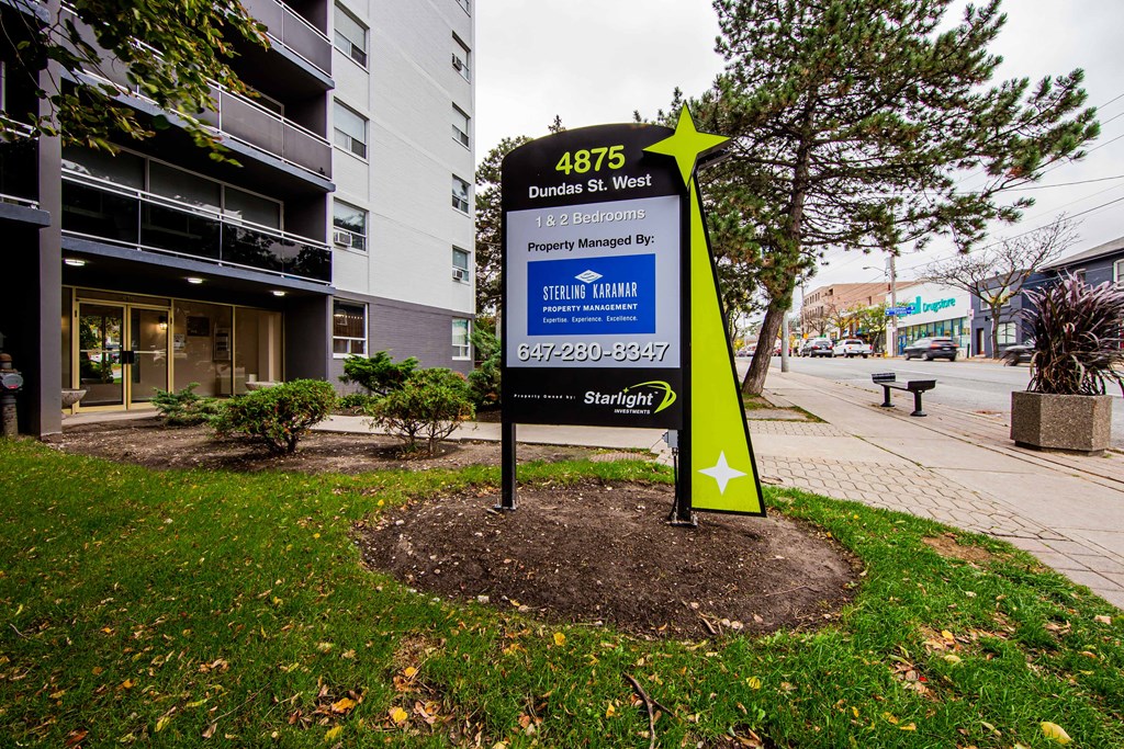 a sign in a grassy area with a building in the background
