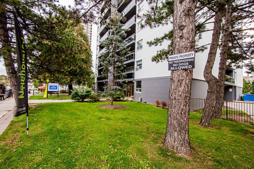a sign on a tree in front of an apartment building