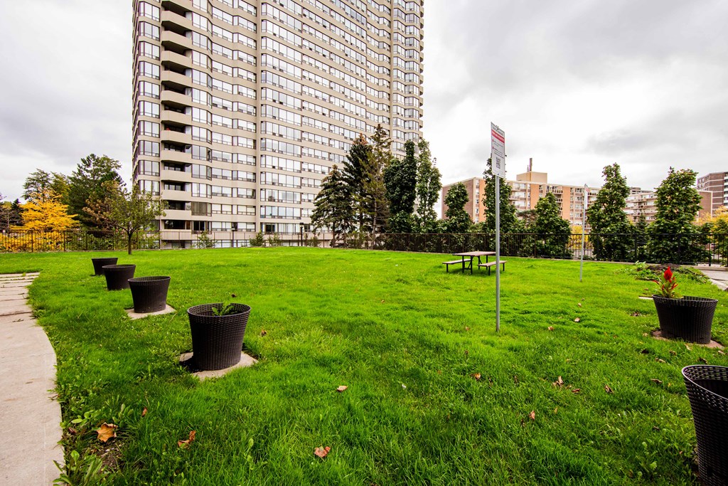 a grassy area with a picnic table in front of an apartment building