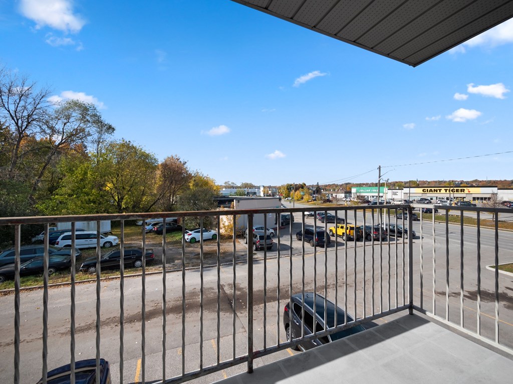 a balcony with a metal railing overlooking a parking lot