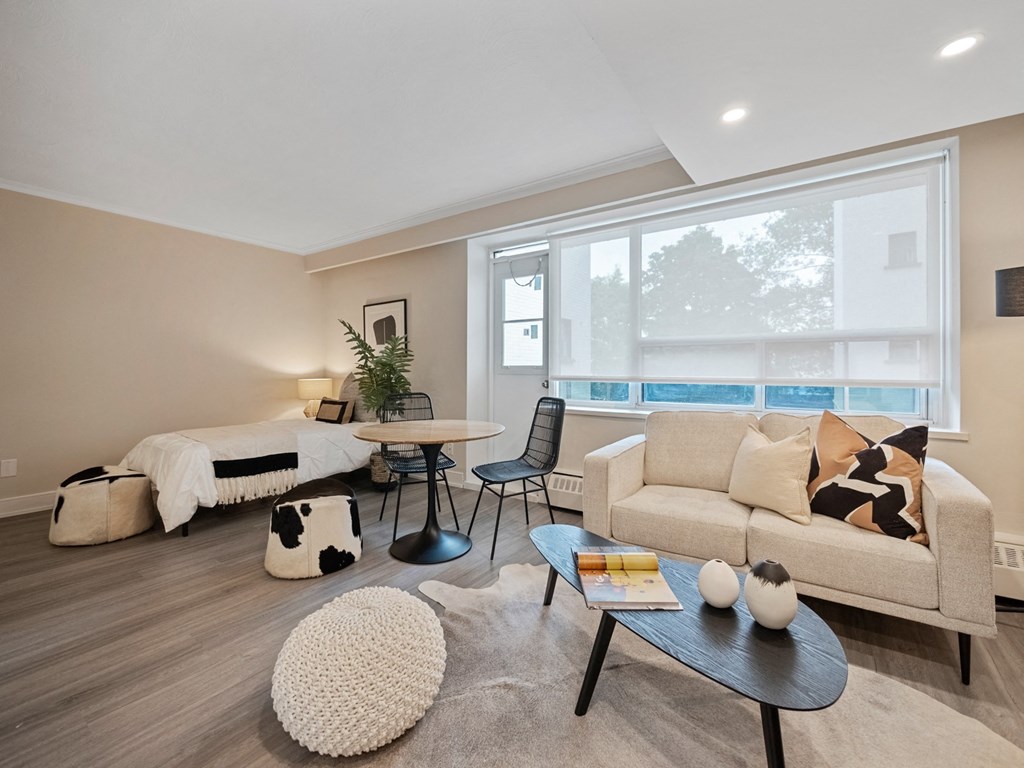 a living room with a couch table and chair and a bed in the background