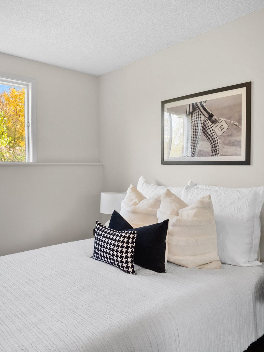 a bedroom with a large bed with white sheets and black and white pillows