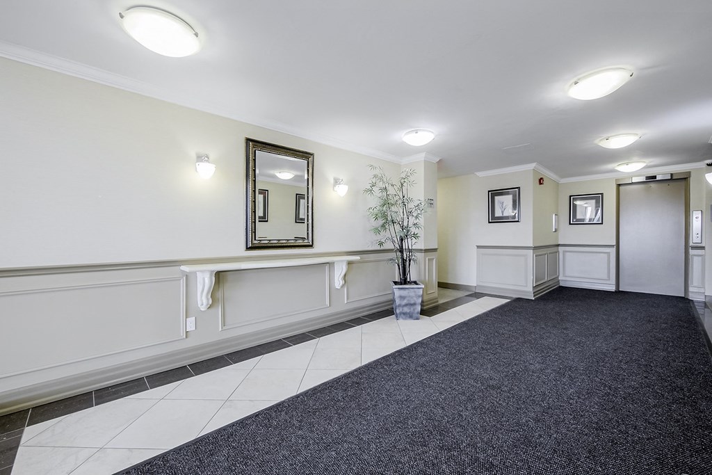 a long hallway with white walls and black carpet