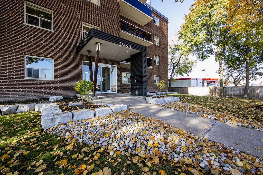 a large brick building with a black awning and a pile of leaves on the ground