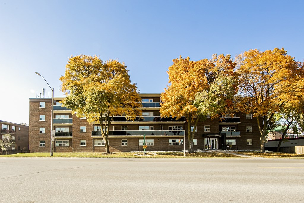 a brick apartment building with three trees in front of it