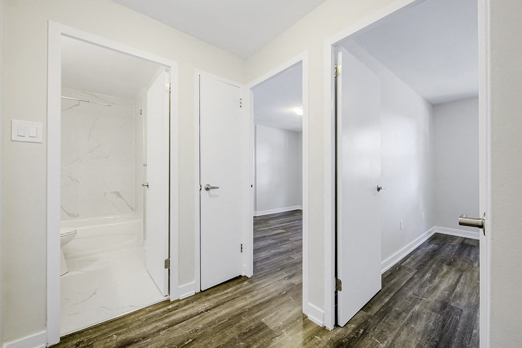 a bedroom with hardwood floors and white walls