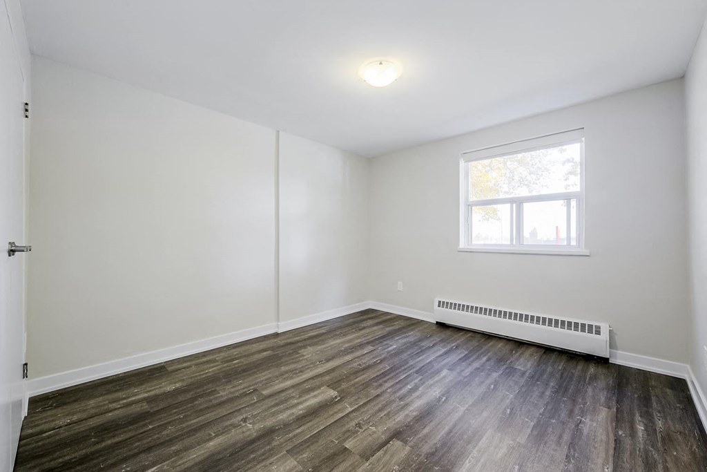 a bedroom with hardwood floors and white walls