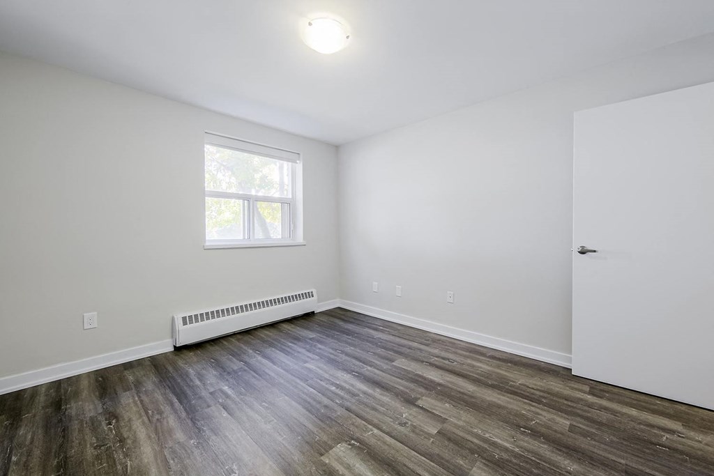 a bedroom with hardwood floors and white walls
