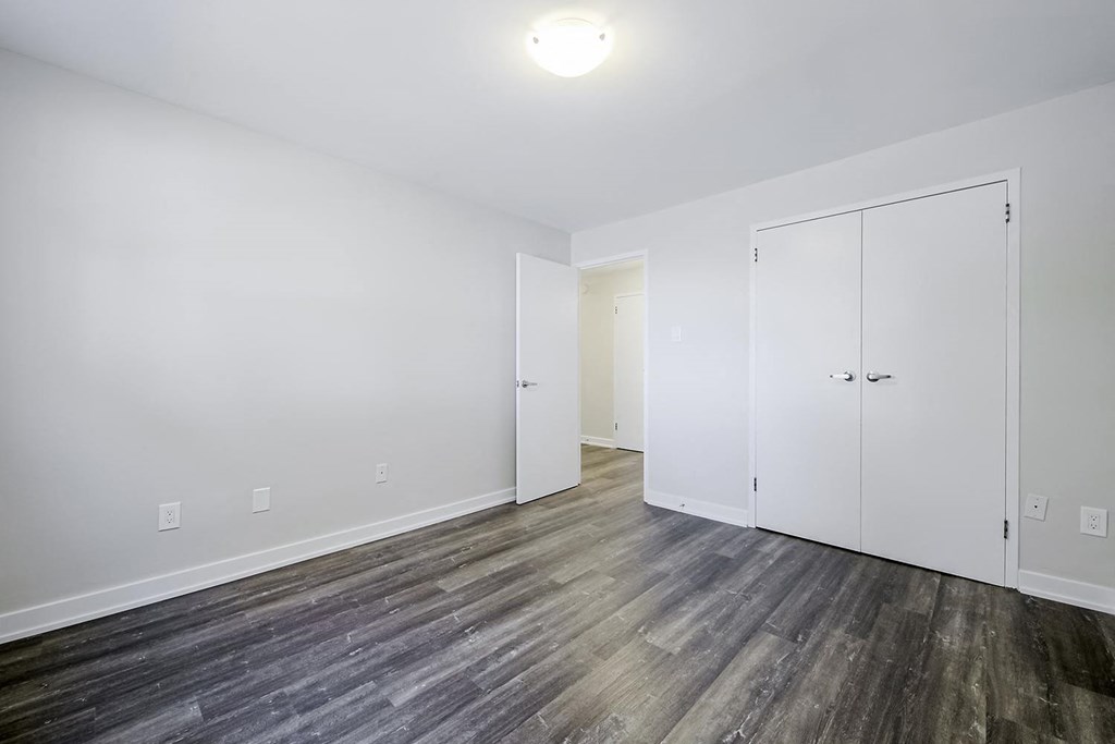 a bedroom with hardwood floors and white walls