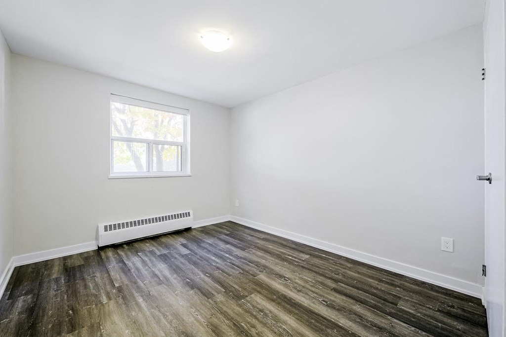 a bedroom with hardwood floors and white walls