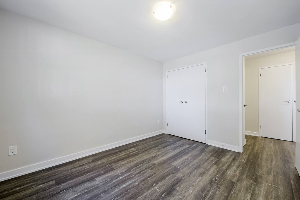 a bedroom with hardwood floors and white walls