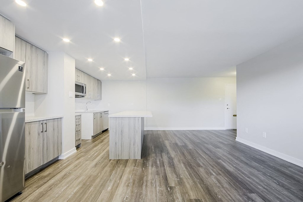 a kitchen and living room with white walls and wood floors