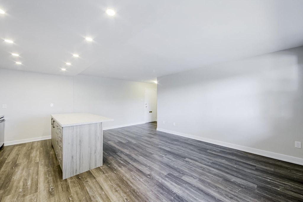a kitchen and living room with white walls and a wooden floor