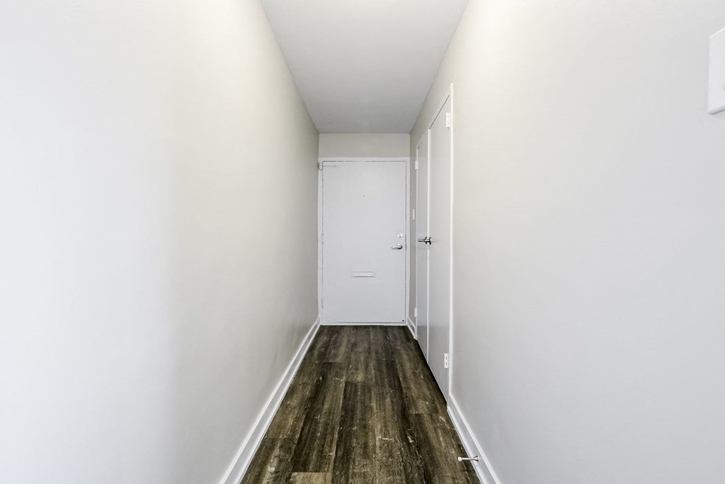 a long hallway with white walls and a white door at the end of the hallway