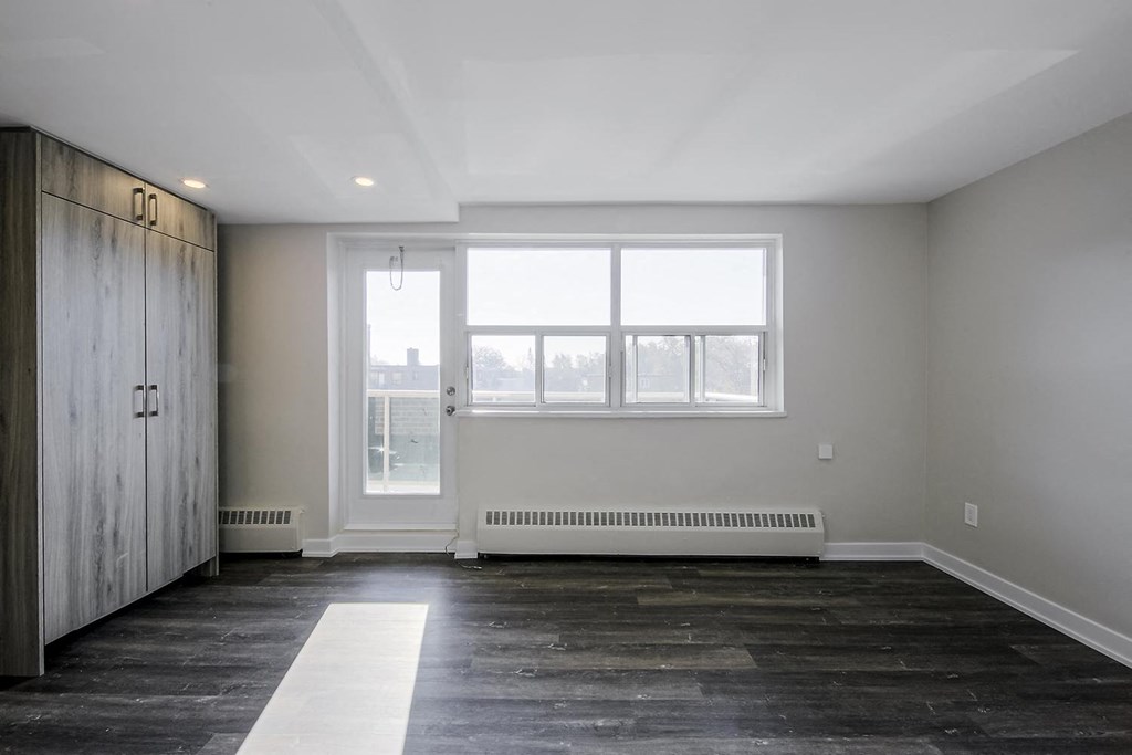 an empty room with a large window and a wardrobe