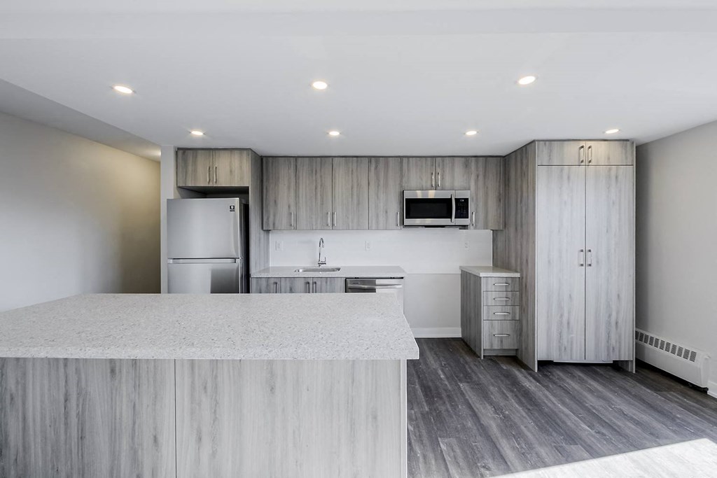 a kitchen with a large center island next to a refrigerator freezer and a stove top oven