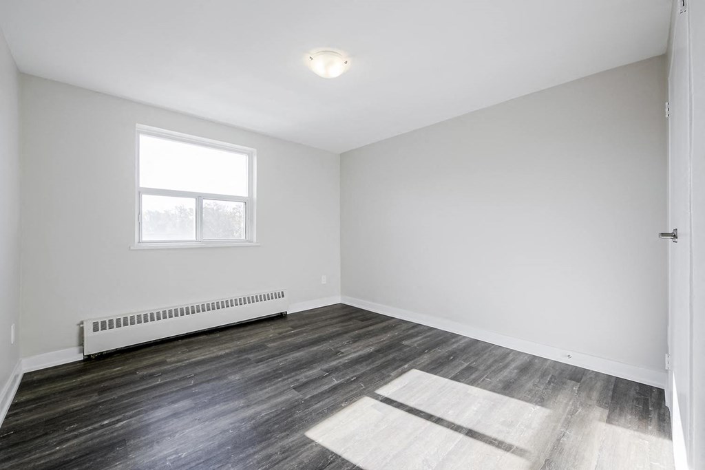 a bedroom with hardwood floors and white walls