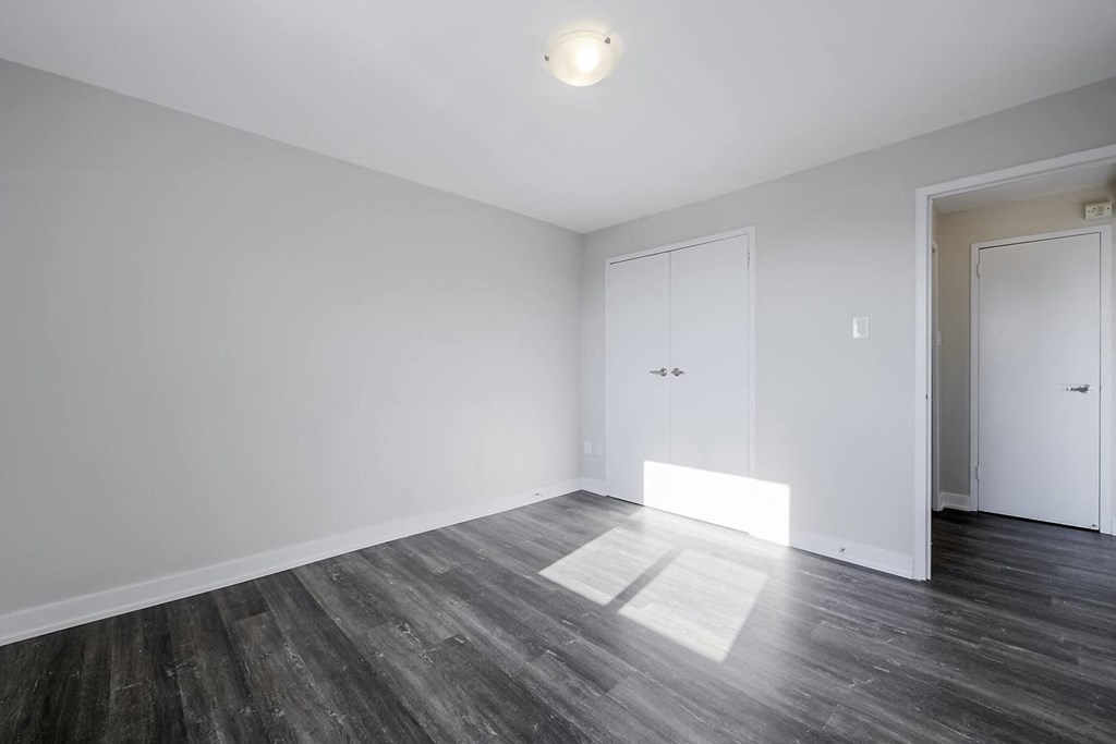a bedroom with hardwood floors and white walls