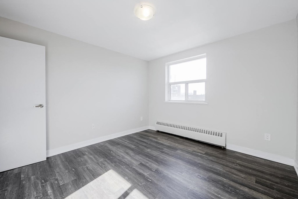 a bedroom with hardwood floors and white walls