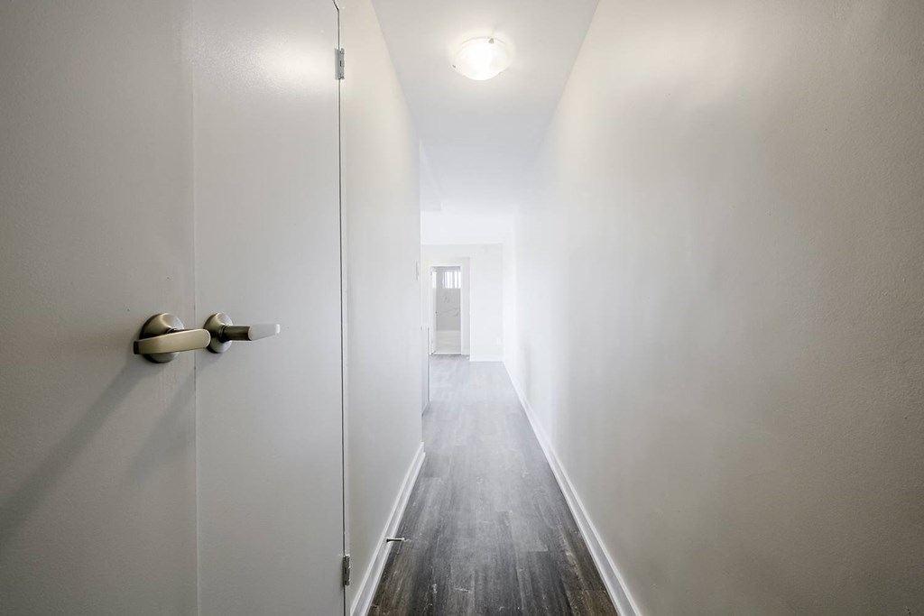a hallway with white walls and a wooden floor