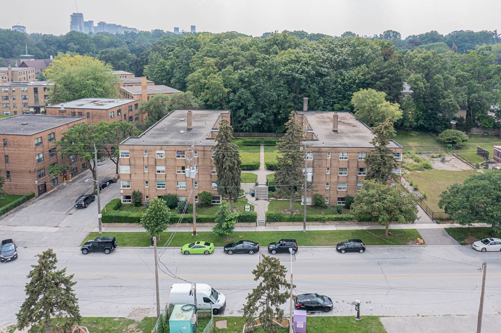 a view from the top of a building of three brick apartment buildings with cars parked in front