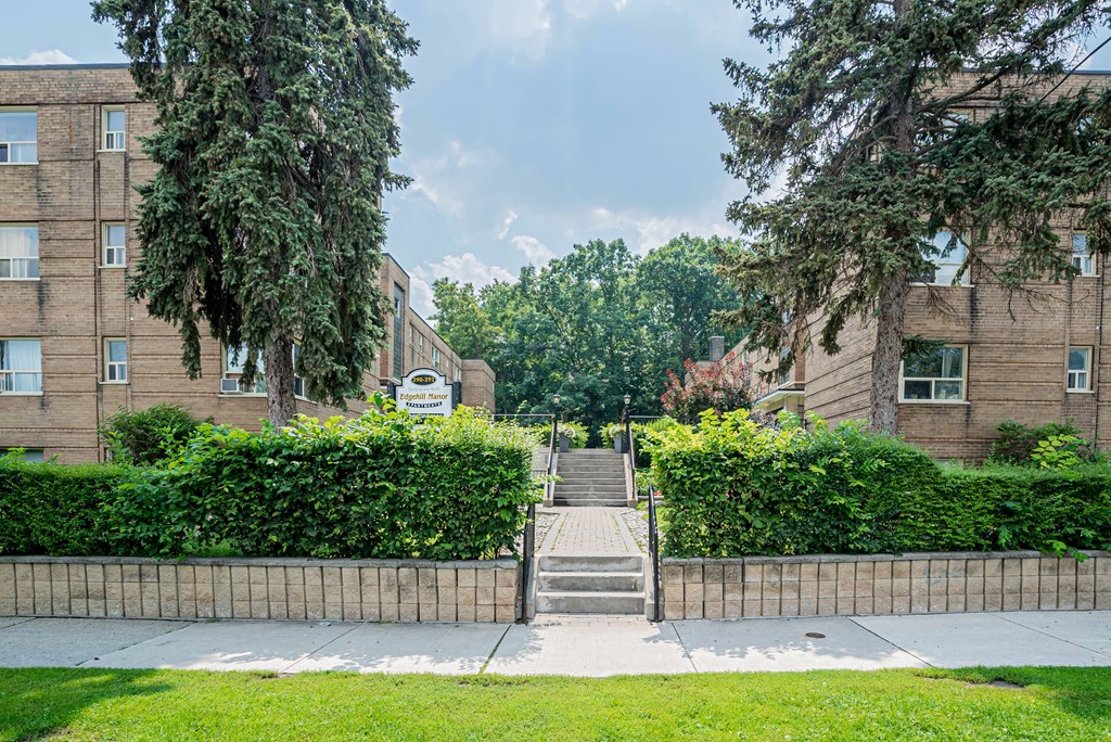 a brick building with stairs and trees in front of it