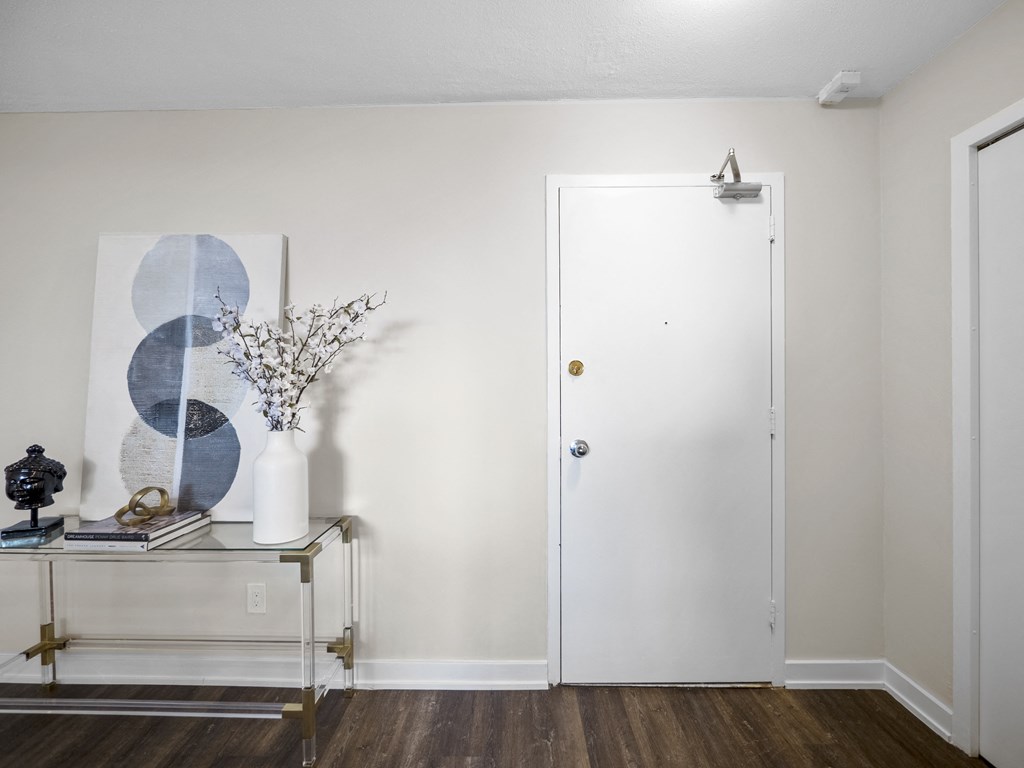 a bedroom with a white door and a glass table with a vase with flowers on it