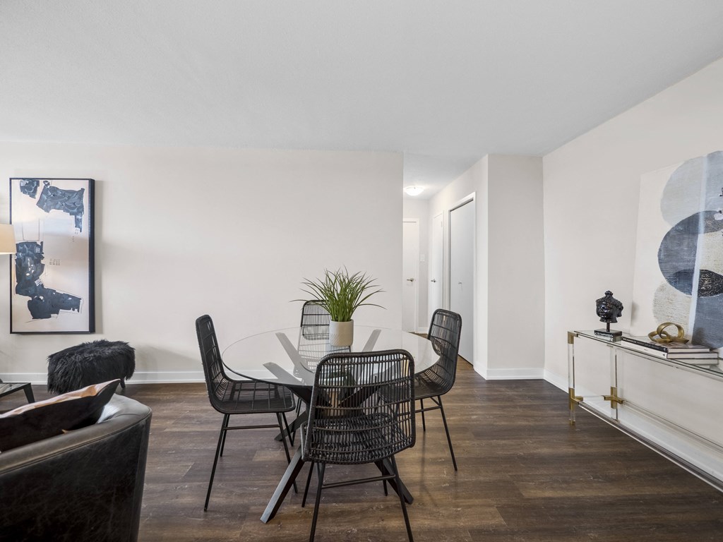 a dining area with a glass table and four black chairs