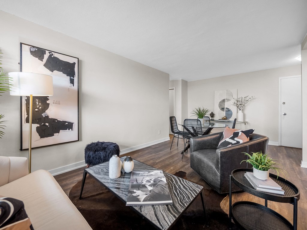 a living room with a couch coffee table and chairs and a dining room table in the background