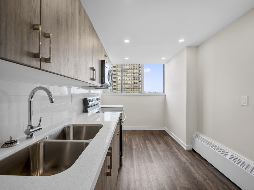 a kitchen with wood floors and white cabinetry