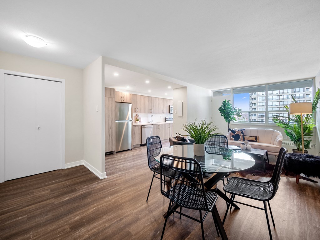 a dining area with a glass table and chairs and a kitchen in the background