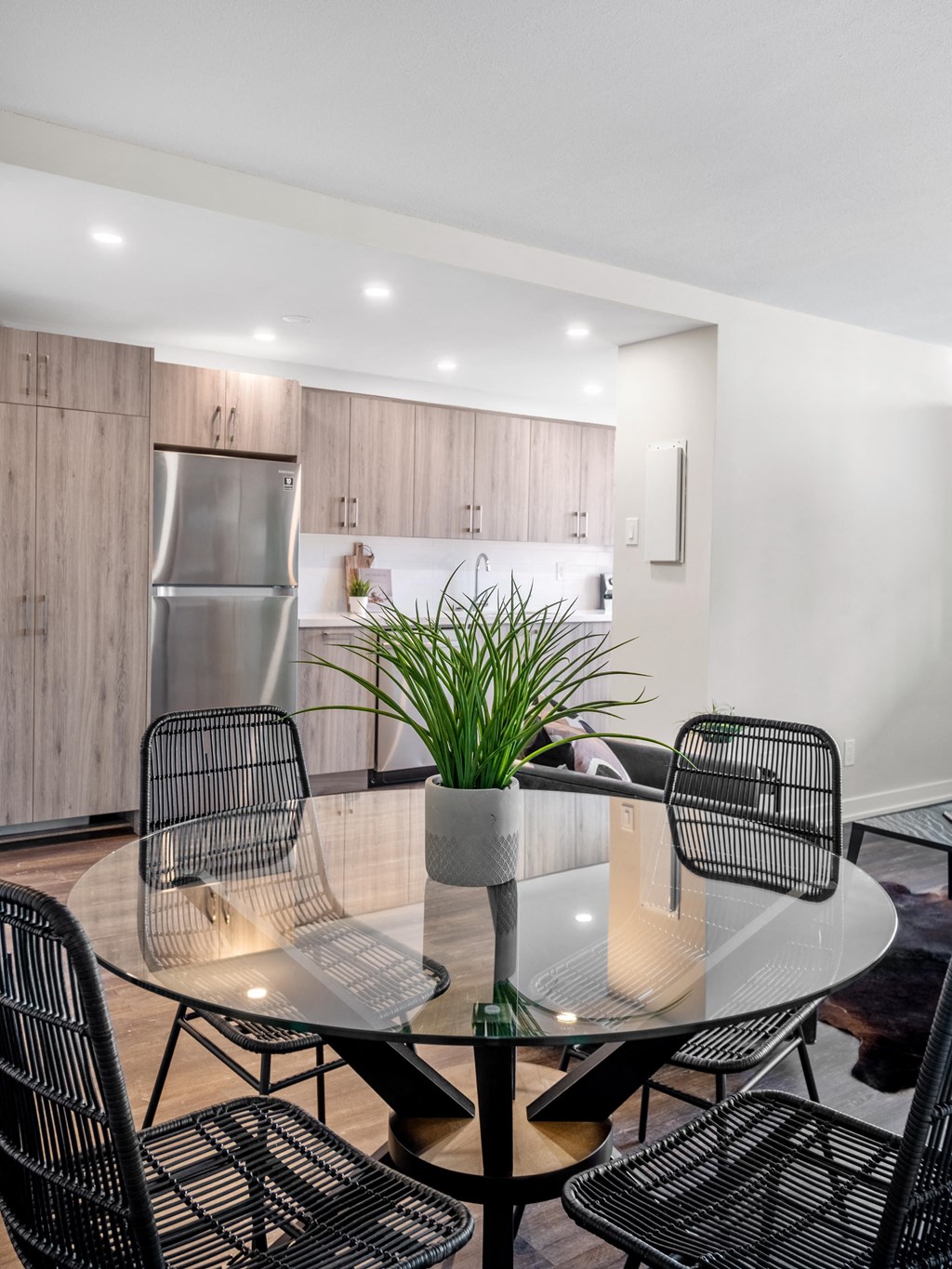 a dining area with a glass table and chairs and a kitchen in the background