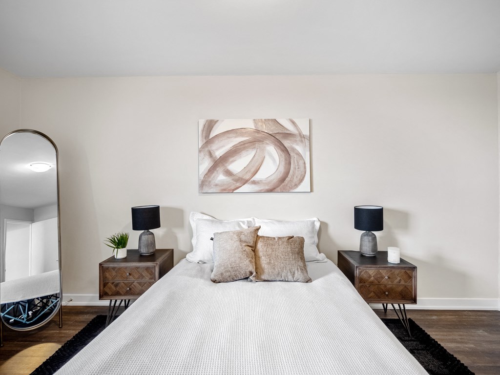 a bedroom with a large bed with white bedding and two night stands with lamps on them