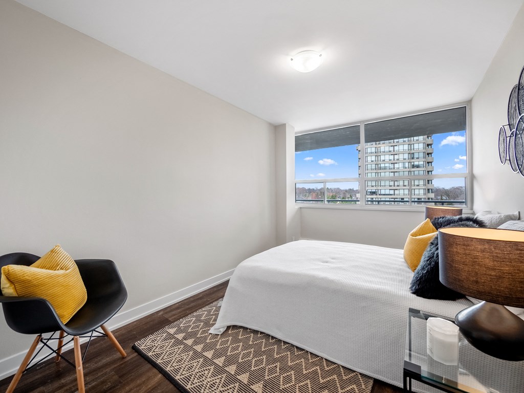 a bedroom with a bed and a chair in front of a window