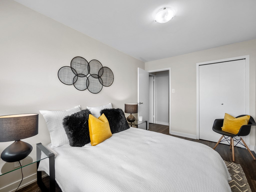 a bedroom with white walls and a large bed with yellow and black pillows