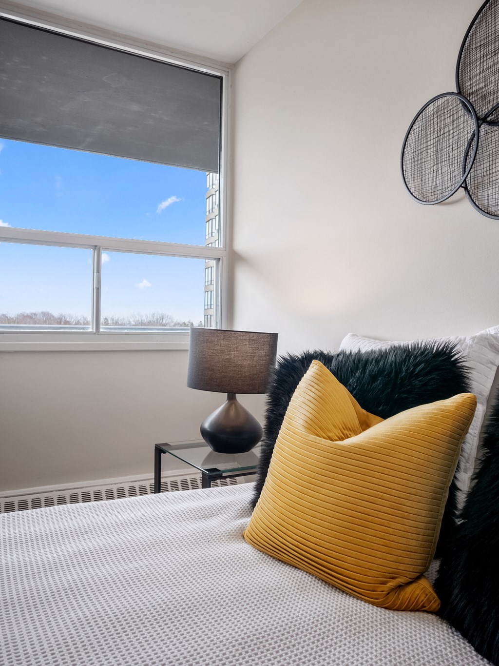 a bedroom with a large window and a bed with a yellow pillow and a black and white
