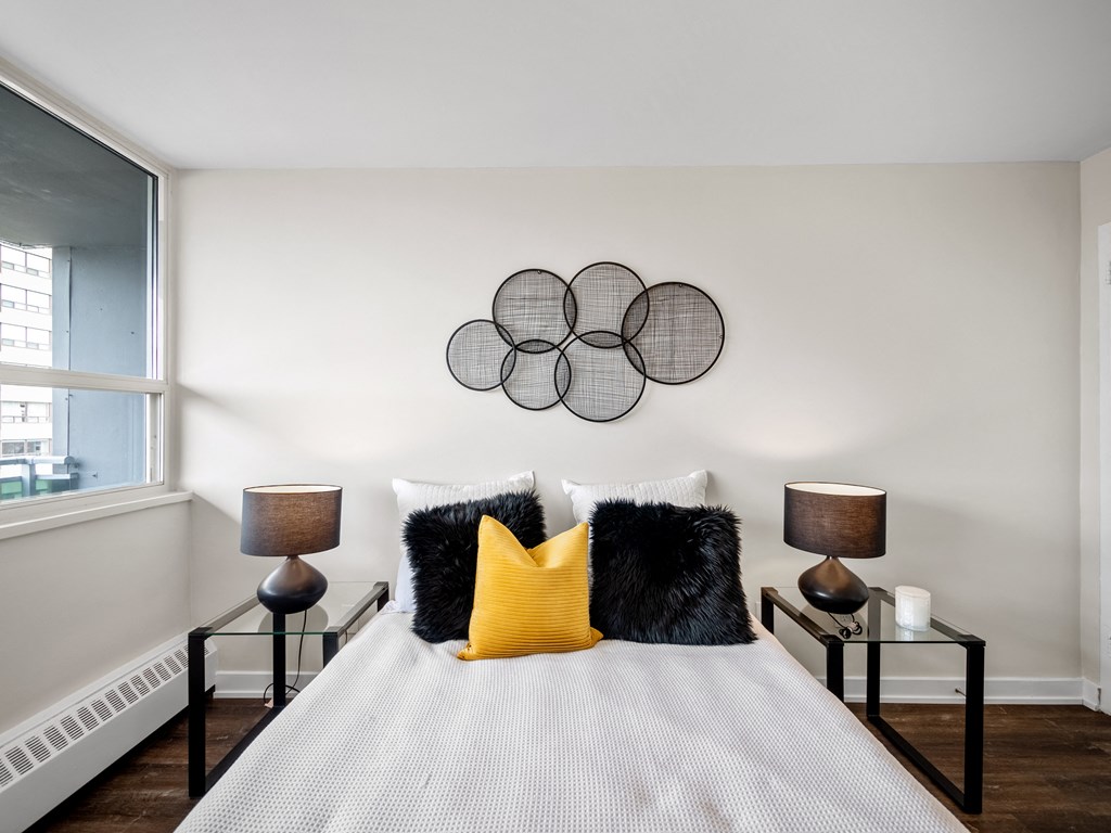 a bedroom with a large bed with a white comforter and black and yellow pillows