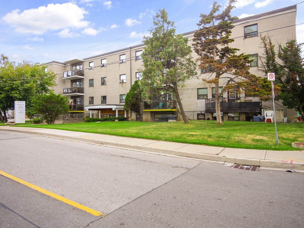 a large apartment building with a green lawn and trees in front of it