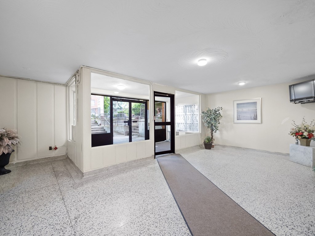 a resident lobby with a tv and a plant on the side of the door