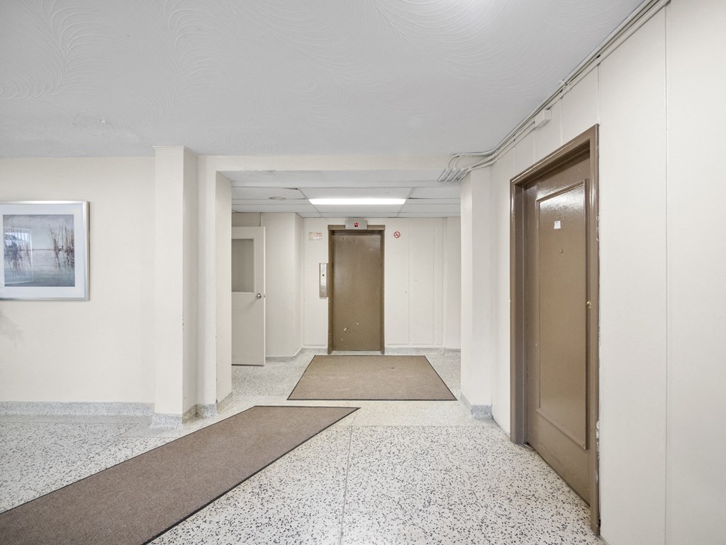 a long corridor with doors and rugs on the floor