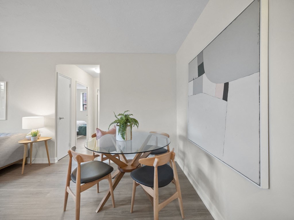 a dining area with a glass table and four chairs