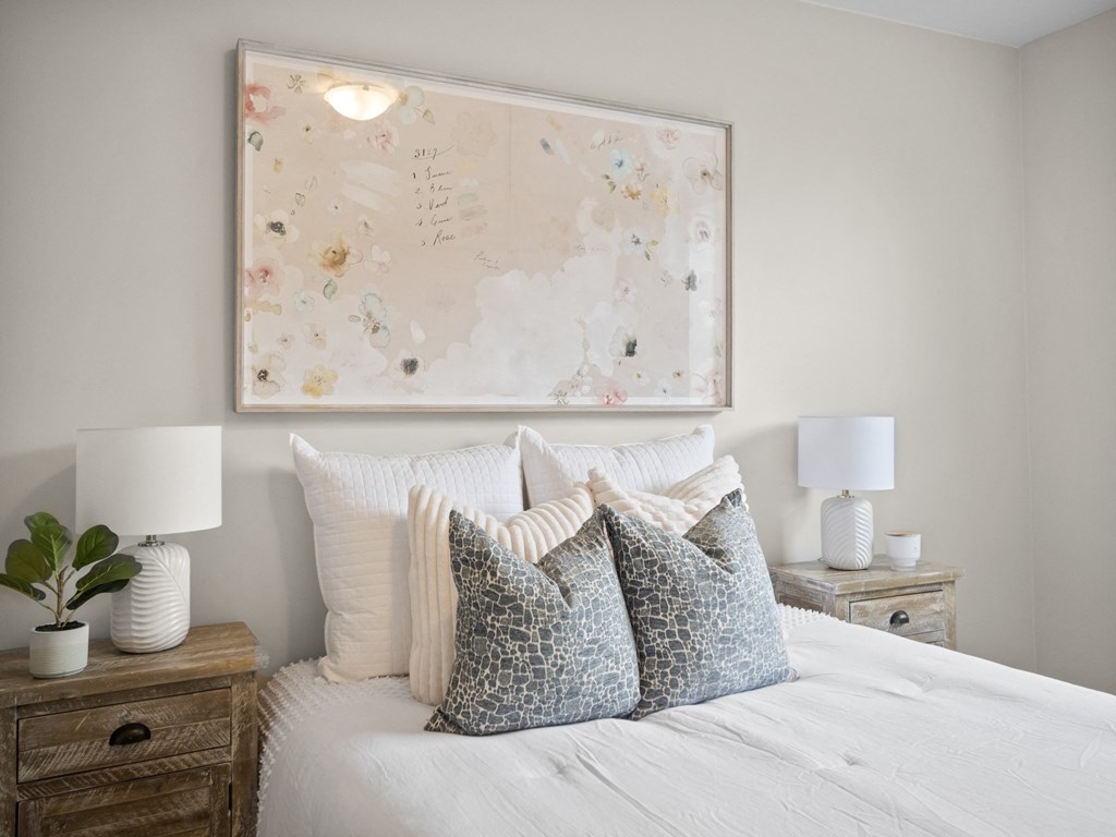 a bedroom with a large painting above the bed and two nightstands with lamps on them