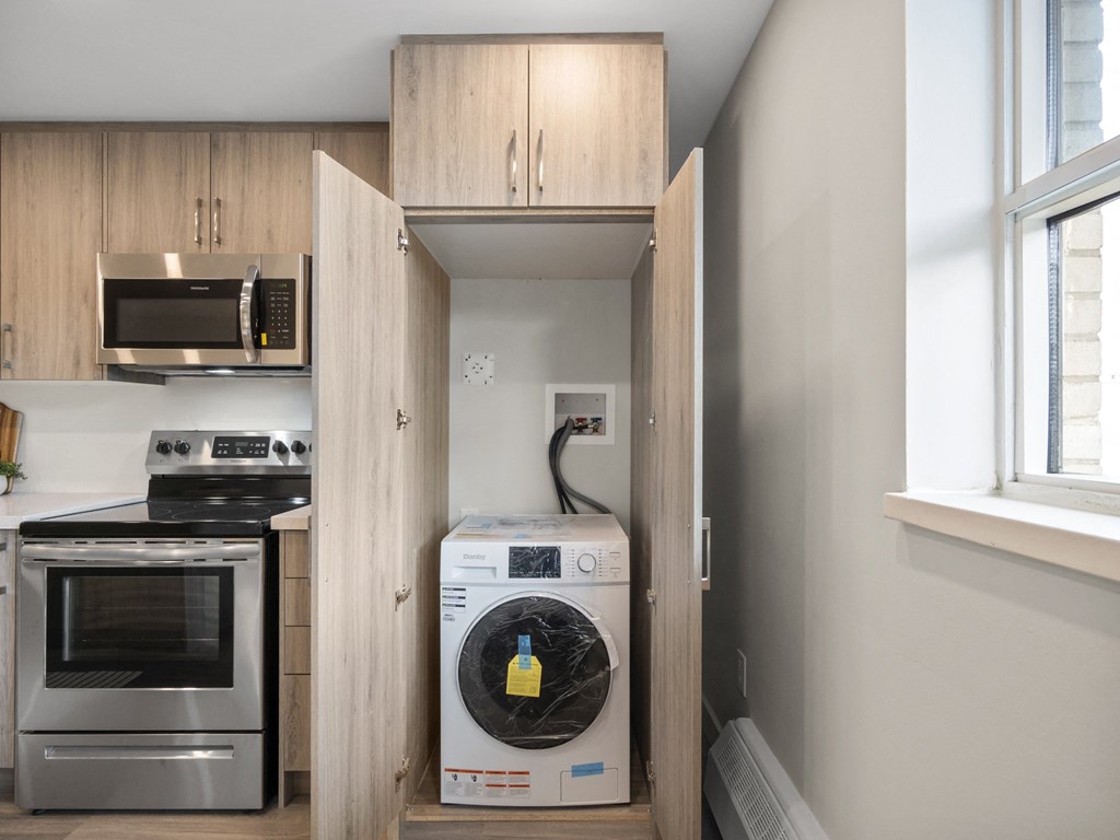a small laundry room with wooden cabinets and a washer and dryer