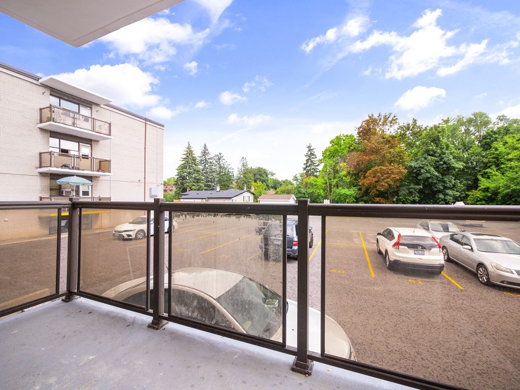 a balcony with a view of a parking lot and trees
