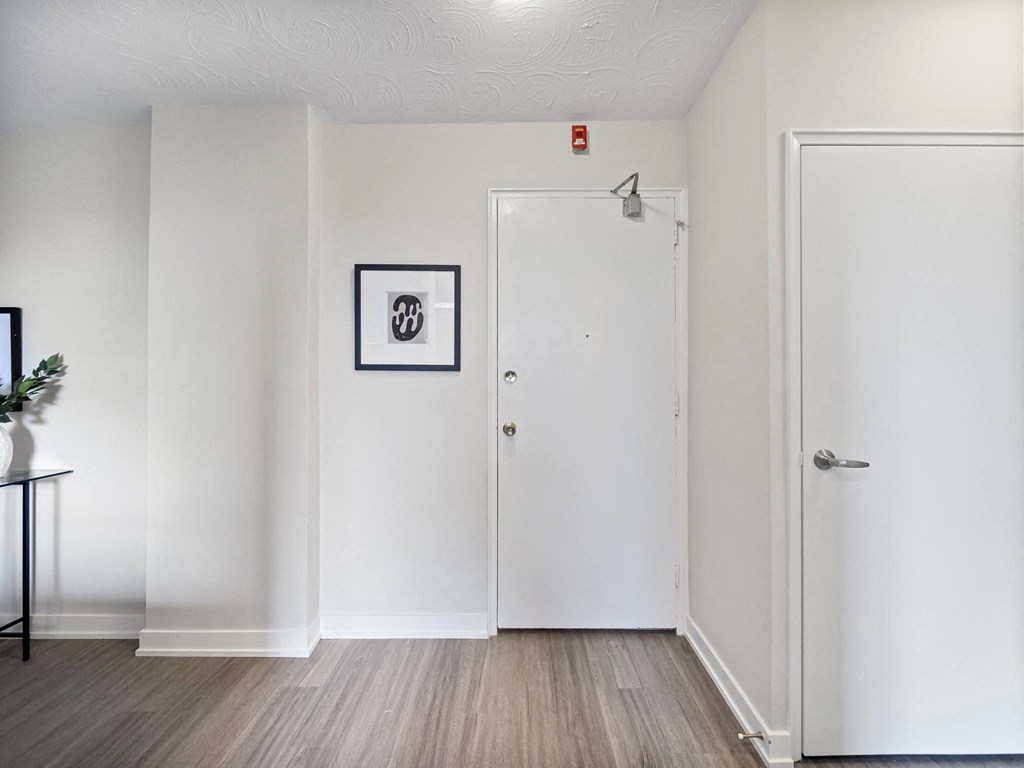 a bedroom with white walls and hardwood floors