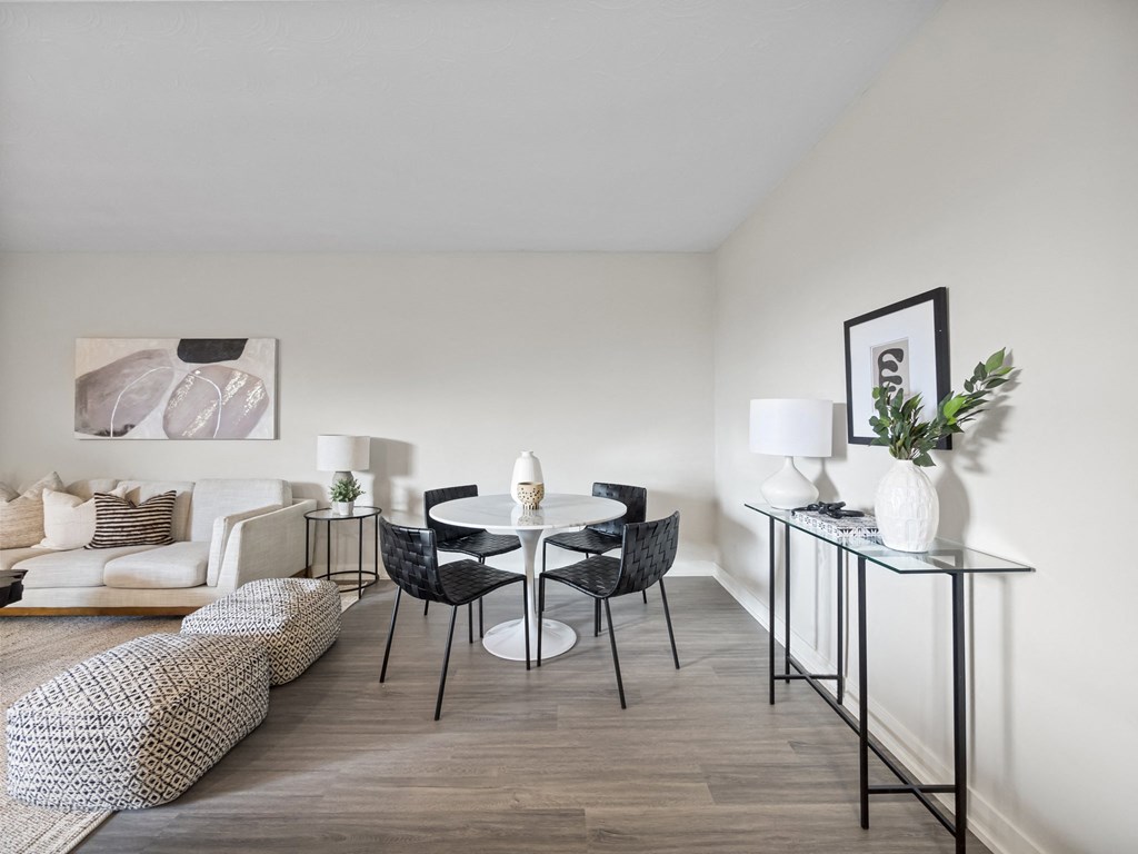 a dining area with a round table and four black and white chairs