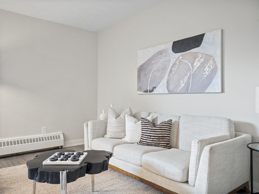 a living room with a white couch and a black and white painting on the wall