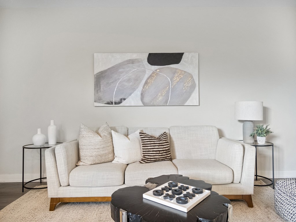 a living room with a white couch and a large painting on the wall